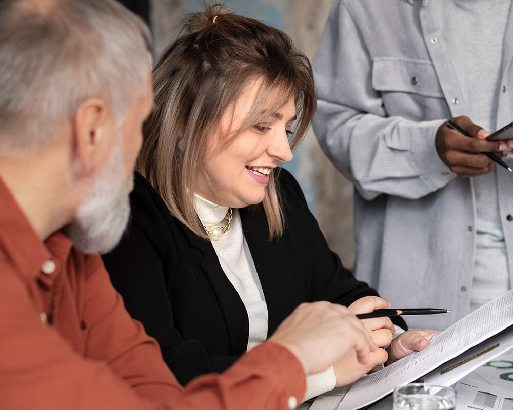 Une femme souriante montre un document à un homme plus âgé à côté d'elle