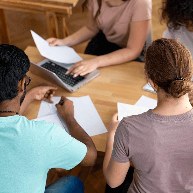 Trois personnes travaillent ensemble sur un bureau en bois