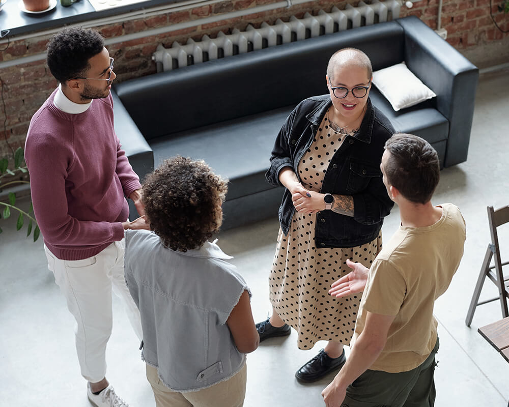 Vue depuis un étage d'un groupe de 4 personnes discutent dans un espace public chaleureux